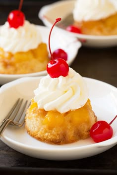 three small desserts with whipped cream and cherries on them are sitting on white plates