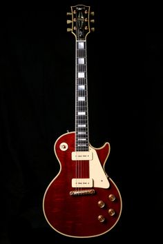 an electric guitar with a red body and neck, on display in a dark room