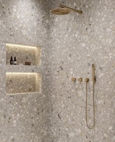 a bathroom with a shower head and two shelves on the wall next to each other