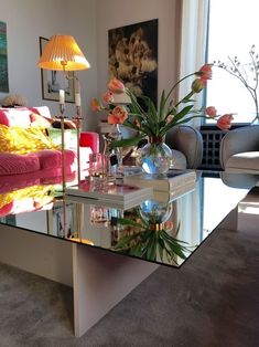 a living room filled with furniture and a glass top coffee table topped with pink flowers