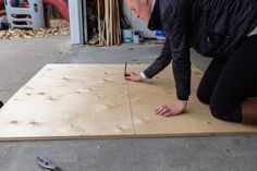 a woman is working on a piece of plywood