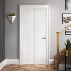 a white door in a room with wood floors and pictures on the wall above it