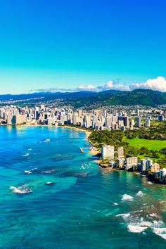 an aerial view of the city of honolulu, with ocean and mountains in the background