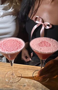 two martinis sitting on top of a wooden table next to another glass filled with liquid