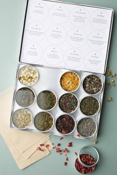 an assortment of loose teas in a metal box on a blue surface with the contents labeled