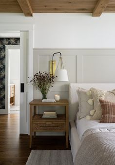 a white bed sitting next to a wooden table on top of a hard wood floor