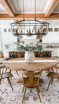 a dining room table with chairs and a chandelier hanging from the ceiling above it