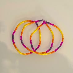 four bracelets are arranged on a white surface and one is orange, the other is pink