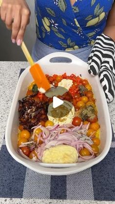 a woman is holding a plastic container filled with vegetables and meats as she prepares to serve herself