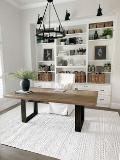 a large wooden table sitting on top of a white rug in front of a bookshelf