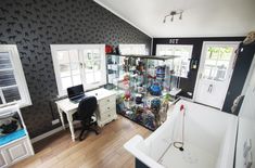 a room with a tub, desk and shelves filled with various items on the wall