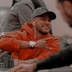 a man sitting at a table with headphones on and pointing to his left side