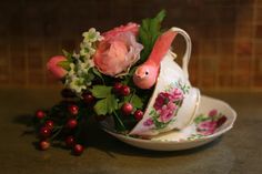 a pink flamingo figurine sitting on top of a tea cup filled with flowers