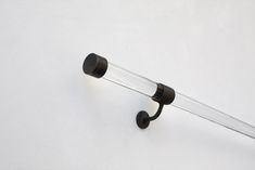 a black handle on a white wall with a glass tube hanging from it's side