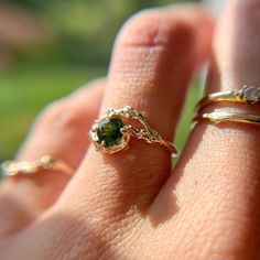 a woman's hand with two rings on it and one has a green stone in the middle