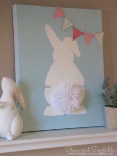 a white bunny sitting on top of a shelf next to a vase filled with flowers