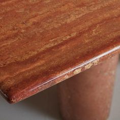 a close up of a wooden table with a vase in the background