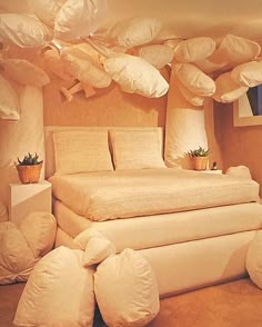 a large bed sitting in the middle of a room filled with pillows and pillows on top of it