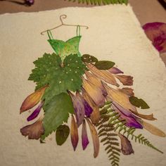 a dress made out of leaves on a piece of cloth with fern fronds