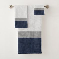 two towels hanging on a towel rack in front of a white wall with blue and grey stripes