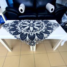 a white table with black and silver designs on it in front of two couches