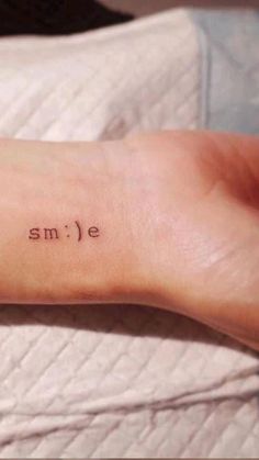 a small smile tattoo on the left inner arm and wrist is shown in black ink