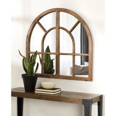 a wooden table topped with a potted plant next to a large mirror on the wall