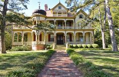 a large yellow house sitting in the middle of a lush green forest filled with trees