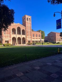 an old brick building with a clock tower on the front and green grass in front