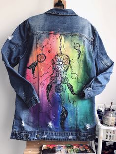 a denim jacket with an image of a dream catcher painted on it