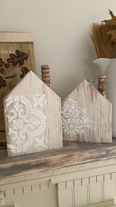 three small wooden houses sitting on top of a table next to a vase and other items