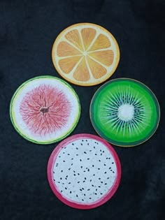 four slices of fruit are shown on a black surface