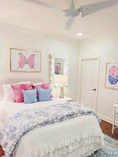 a white bed with pink and blue pillows