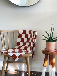 a chair with a checkered blanket next to a potted plant