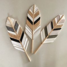 three pieces of art made out of wood and painted with black, white and gold stripes