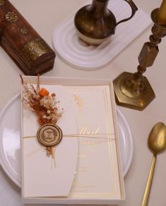 a table topped with white plates and goldware