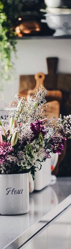 two white pots filled with flowers on top of a counter