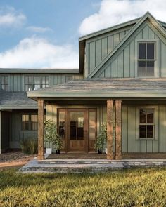 a dog is sitting on the front porch of a large house with two garages