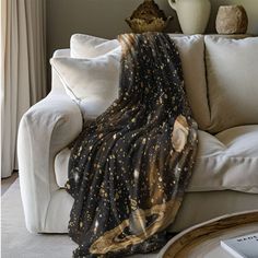 a black and gold star print blanket draped over a white couch in a living room