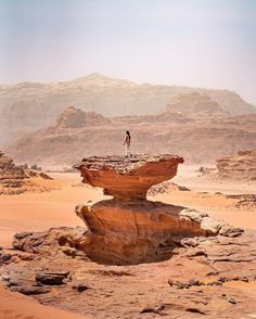 a man standing on top of a rock formation in the middle of wadih desert