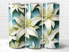 three vases with white and blue flowers on the front, one has green leaves