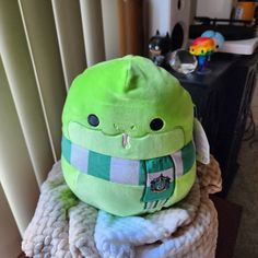 a green stuffed animal sitting on top of a pile of blankets