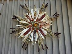 a clock made out of feathers on the side of a metal building with words written on it