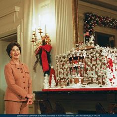 a woman standing in front of a large gingerbread house with christmas decorations on it