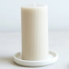 a white candle sitting on top of a plate