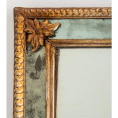 an ornate gold framed mirror with a leaf decoration