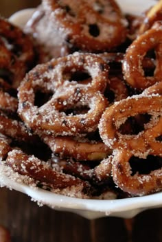 a bowl filled with sugar covered pretzels on top of a wooden table