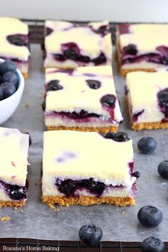 blueberry cheesecake bars are cut into squares and placed next to bowls of fresh berries