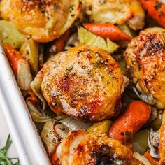 chicken, carrots and onions in a white casserole dish with herbs on the side