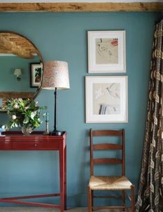 a room with blue walls and pictures on the wall, a red desk and chair